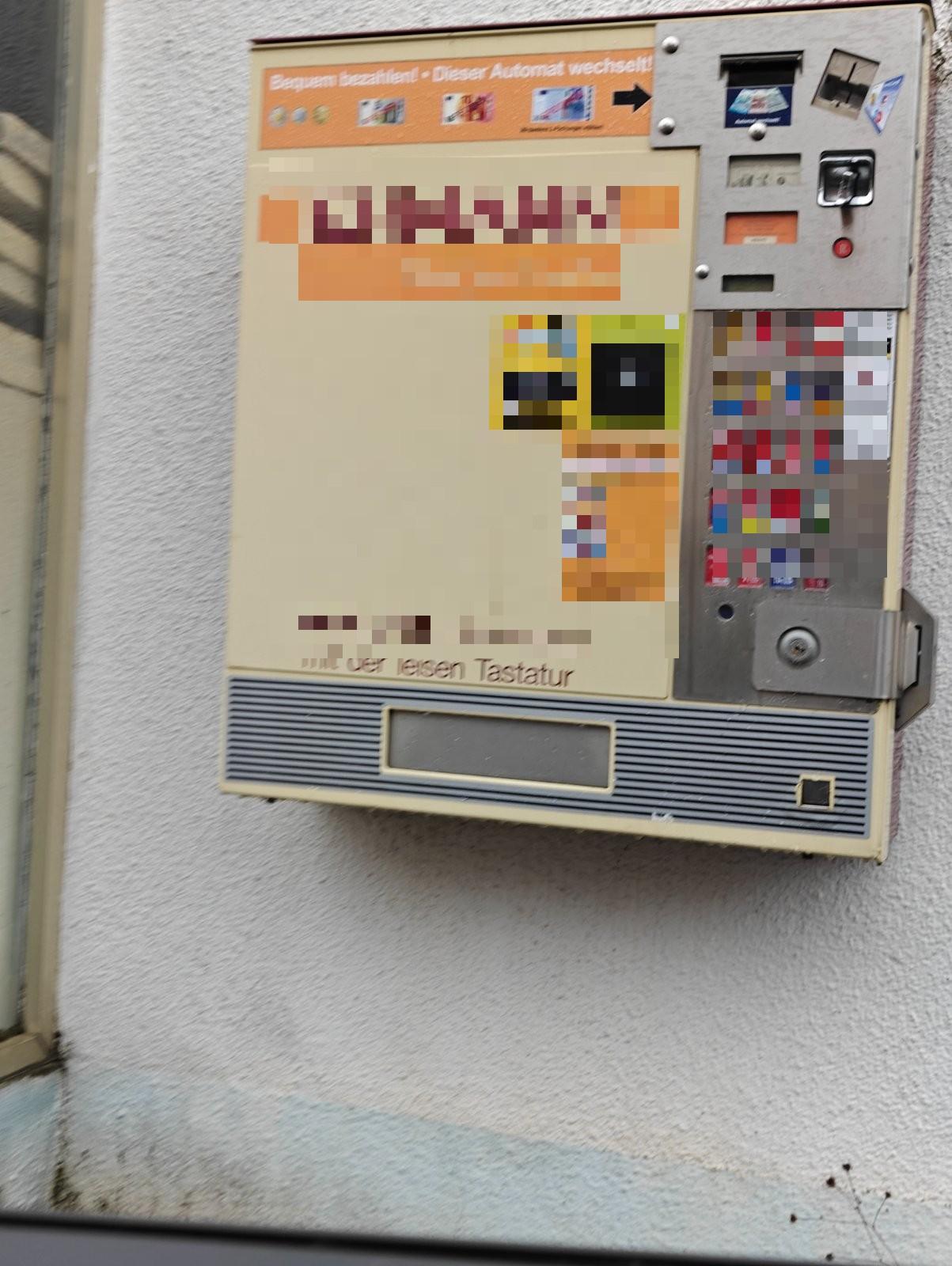 Älterer Zigarettenautomat an einer Hauswand mit senkrechtem Kartenschlitz, Scheineinzug, Münzeinwurf und Tastenfeld