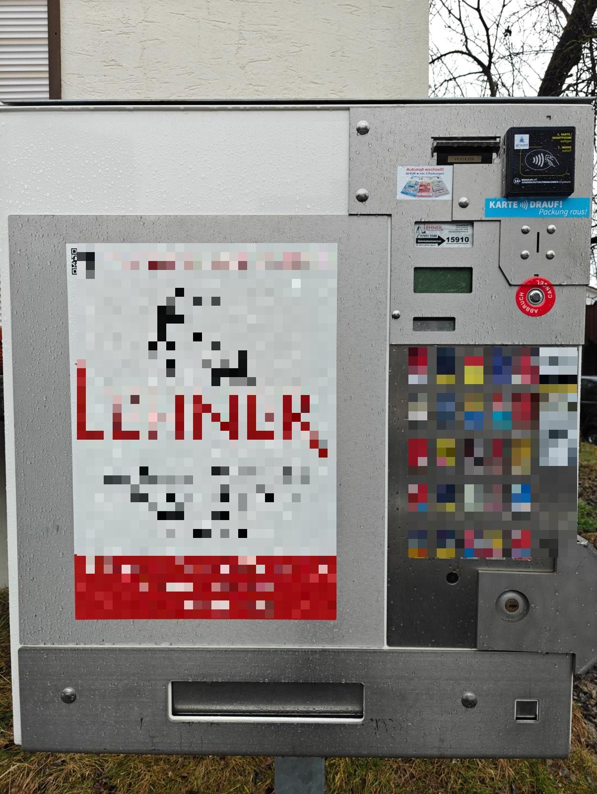 Zigarettenautomat mit Lesefeld für kontaktlose Karten oben rechts, daneben Aufkleber „Karte drauf, Packung raus“, darunter Münzeinwurf und Ausgabefach